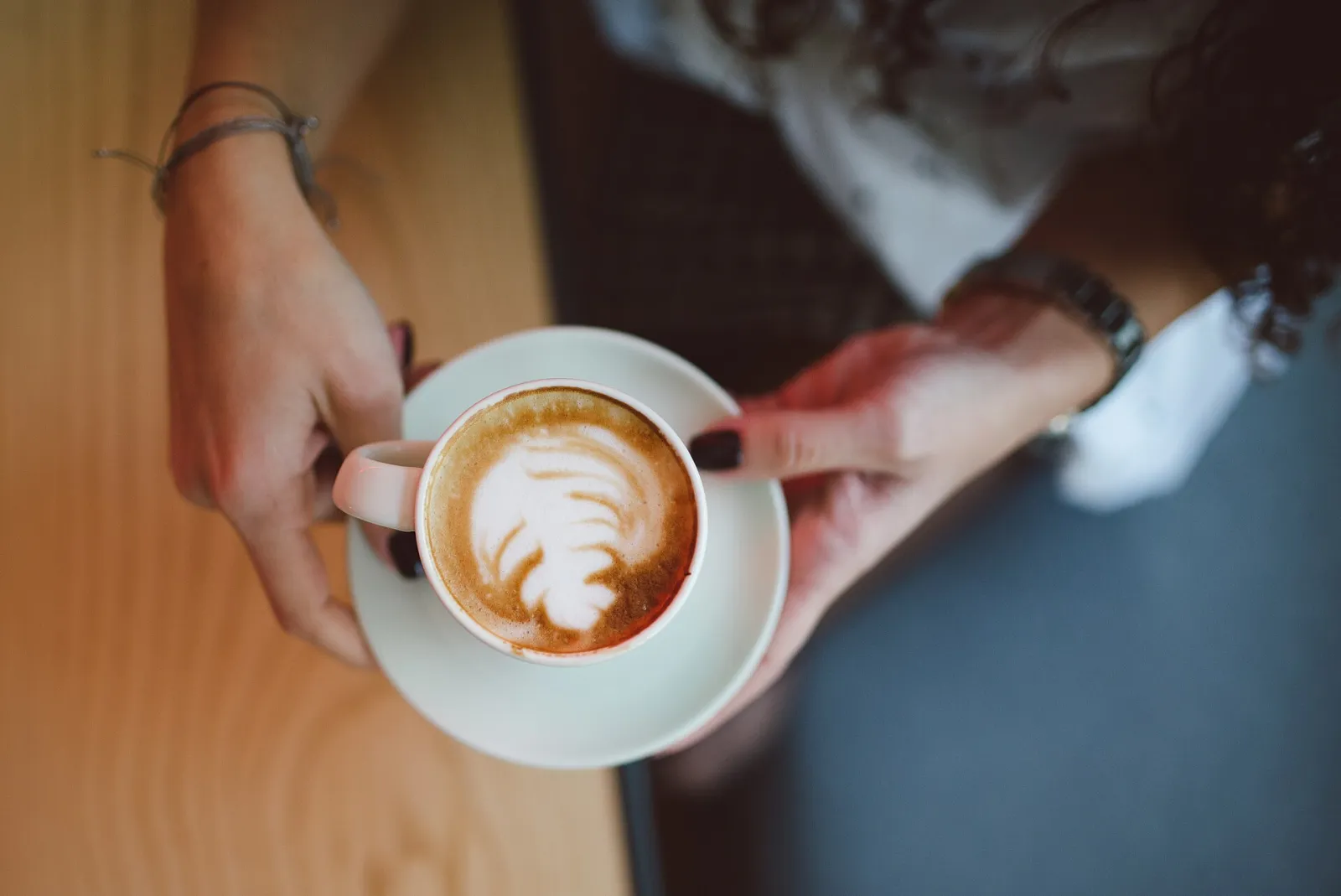 A cappuccino with latte art on a cafe table. The photo was not taken in Boca Raton.