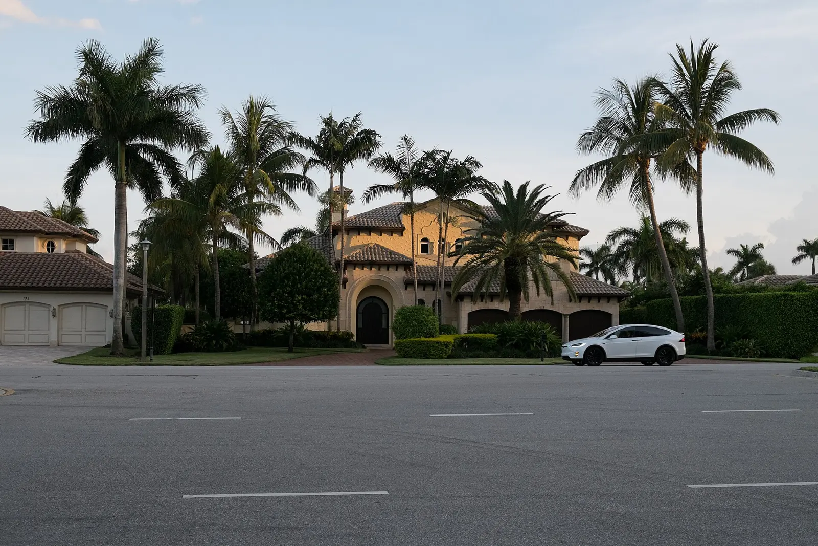 A tile-roofed house behind a row of palms on a Boca Raton street.